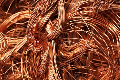 Coiled copper wire scrap mixed into steel recycling feedstock, illustrating the copper contamination problem in EAF steelmaking