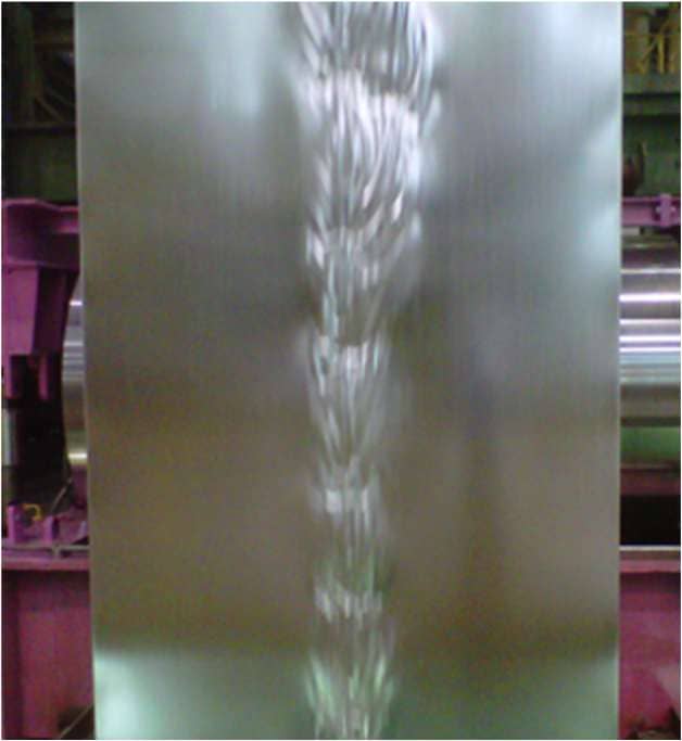 Photograph of heat buckle developing near the centre of thin, wide steel strip in a galvanising furnace