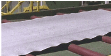 Photograph of severe edge wave in cold rolled steel strip on a conveyor roller table