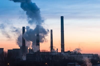 Operating steel plant with visible emissions at dusk showing ongoing carbon-intensive production