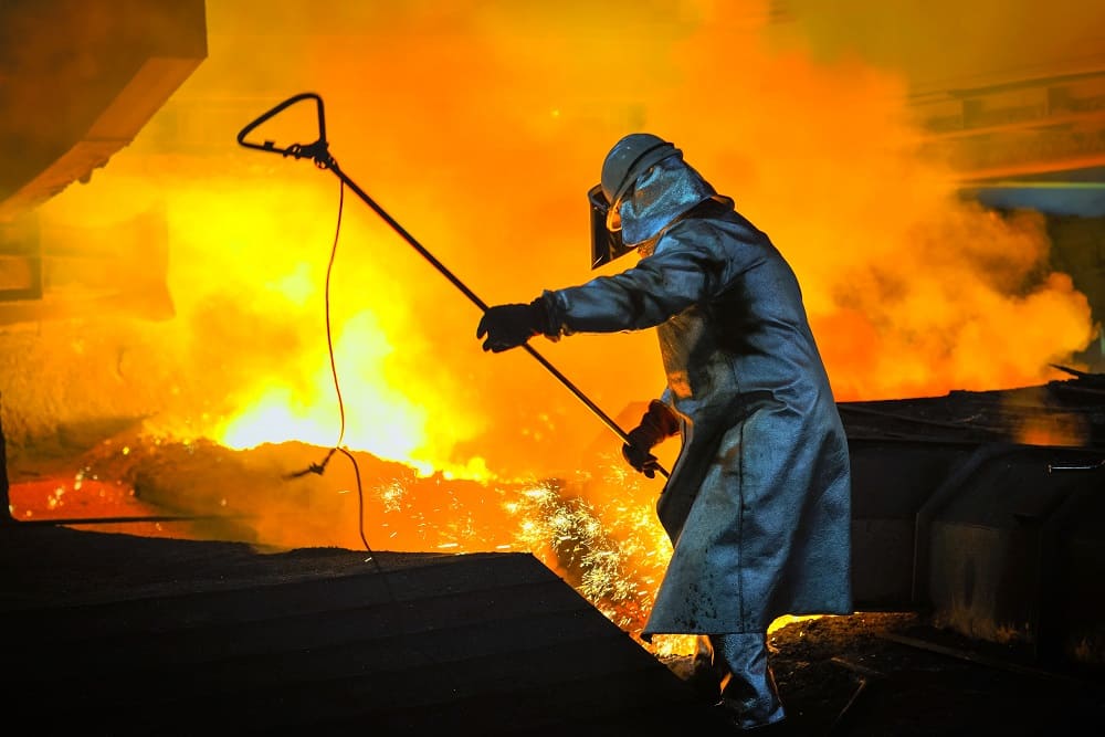 Steel foundry worker managing molten steel production in high-temperature industrial environment